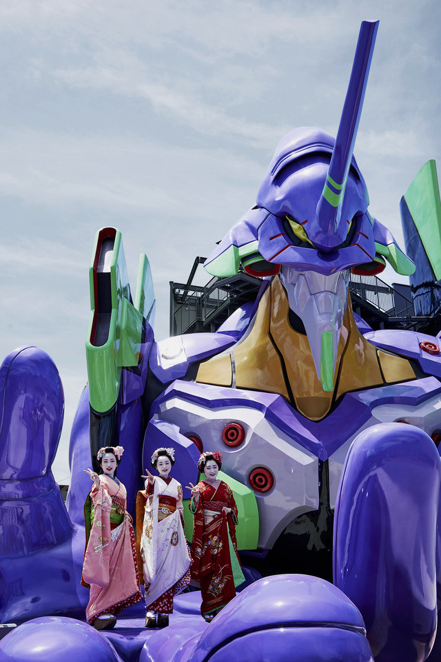 Evangelion Kyoto Base hero image 03 Tiga aktris berpakaian geisha berpose di telapak tangan Unit Eva-01 di atraksi Evangelion Kyoto Base di Toei Kyoto Studio Park.
